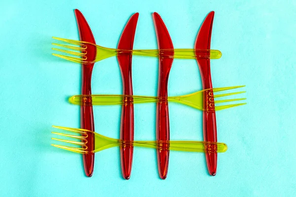 Cuchillos Desechables Plástico Rojo Tenedores Amarillos Aislado Sobre Fondo Turquesa — Foto de Stock