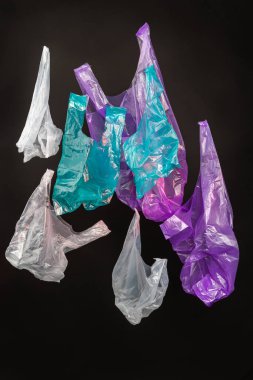 Renkli plastik poşetlerin dikey çekim koleksiyonu. Siyah arkaplanda izole.