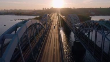 Akşamleyin köprüde hava üstü araba trafiği. Yol ve demiryolları. Gün batımı ışığı yola yansıyor.