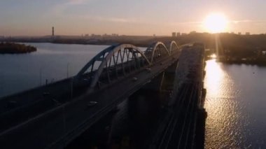 Akşamları köprüde hava manzaralı araba trafiği. Gün batımı ışığı yola yansıyor. Hızlı hız hareketi.