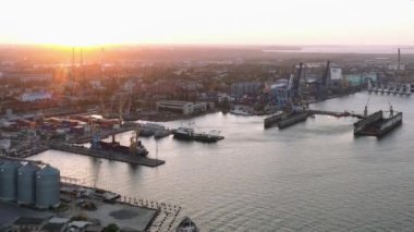 Drone view of urban sea port with grain terminals. Evening sunset light.