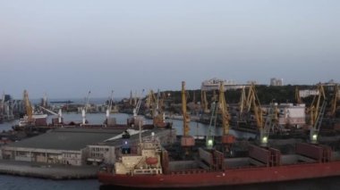 Warehouse and tower cranes on a sea port in the evening. Industrial scape at twilight sky.