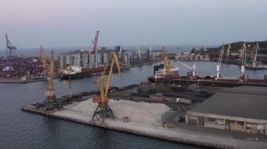Odesa, Ukraine - 08.08.2020: Aerial view of sea port in the evening. Warehouse with grain and tower cranes.