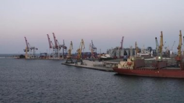 Odesa, Ukraine - 08.08.2020: Drone view of sea port with ship and tower cranes. Evening twilight sky.