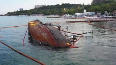 Odesa, Ukraine - 09.08.2020: Overturned rusty oil tanker ship in the shallow water. Drowned sunken ship on its edge. Marine sea scape.
