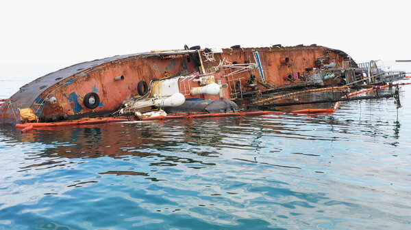 Broken rusty oil tanker ship in the shallow water. Sunken drowned ship after the crash.