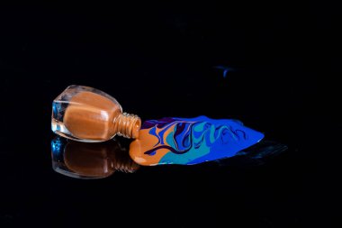 Mixing of blue and brown nail polish colors. Isolated on black.