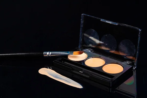 Close up of cosmetic powder palette with brush. Isolated on black.