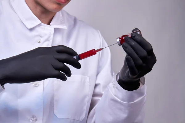 Doctor with black glove filling syringe with medication. Vaccination and immunization.