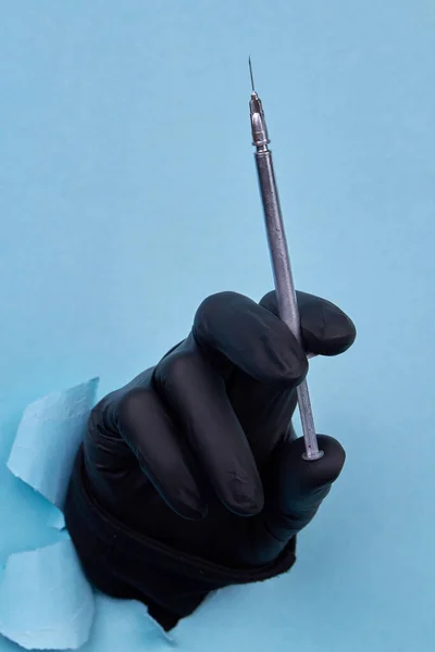 Hand Hält Graue Kosmetikspritze Auf Blauem Hintergrund Schwarzer Gummi Latexhandschuh — Stockfoto