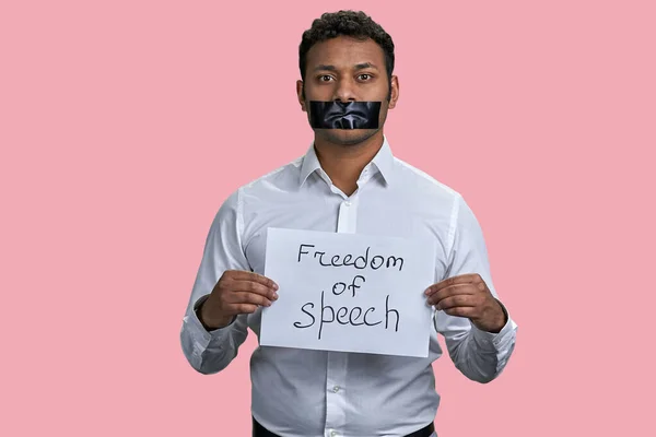 Indian man with taped mouth and freedom of speech inscription. Isolated on pink background.