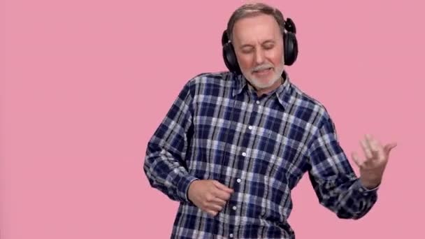 Старший Чоловік Носить Навушники Грає Уявній Гітарі Ізольовані Рожевому — стокове відео