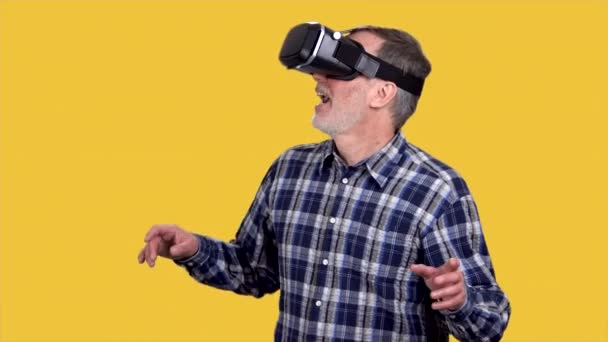 Starší Muž Sluchátkách Zkoumá Virtuální Realitu Izolováno Oranžové — Stock video