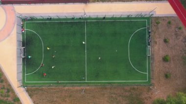 Futbol oynayan erkeklerin hava aracı görüntüsü. Yüksek hız hareketi. Yeşil yapay futbol sahası.