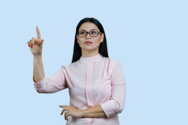 Genç ve zeki Asyalı bir iş kadınının portresi parmaklarıyla dokunuyor. Soluk mavi üzerinde izole.