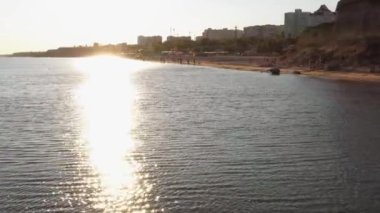Şehir sahilinde parlak güneşli bir yol. Su yüzeyi ve akşam güneşi.