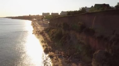 Şehir plajının ve uçurumun üzerinden uçan İHA 'nın görüntüsü. Akşam gün batımı gökyüzü.