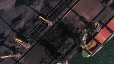 Bir deniz limanının insansız hava aracının üst görüntüsü. Turnalı ve tankerli siyah kömür yığınları.
