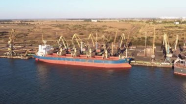 Yükleme için gemi ve vinçleri olan deniz limanı. Turnalar ve kömür yığınları bir deniz limanında.