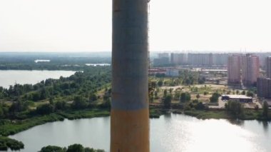 Endüstriyel bir fabrikanın bacasından dron görüntüsü. Şehir nehri ve arka plandaki yerleşim bölgesi.