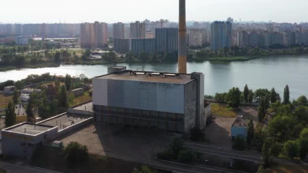 市内の川の前に蒸気放出と産業用建物の屋根 大気汚染と都市河川汚染の概念 — ストック動画