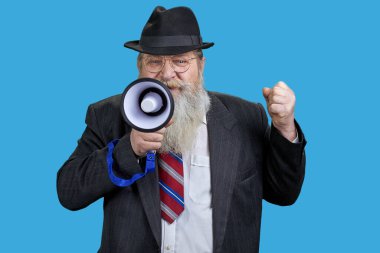 Karizmatik yaşlı bir adamın megafonla konuşma portresi. Mavi arkaplanda izole.