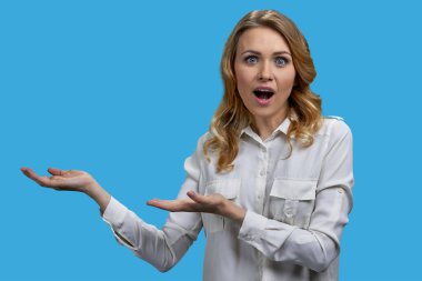 Genç sarışın kadın iki eliyle fotokopi odasını gösteriyor. Canlı mavi arkaplan.