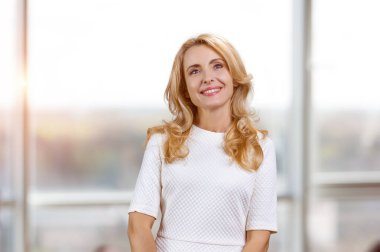 İçerideki düşünceli, orta yaşlı kadın portresi. Arka plandaki bulanık pencere.