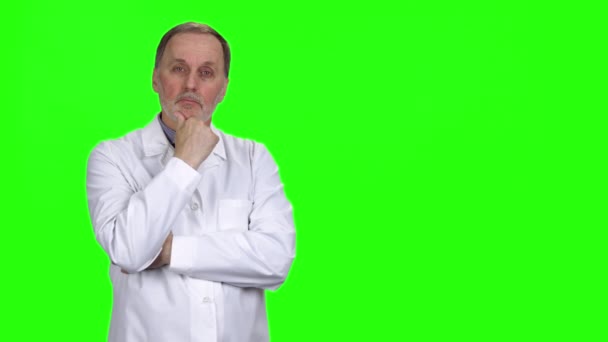 白いコートの思慮深い年老いた男性医師の肖像 グリーンで孤立 — ストック動画