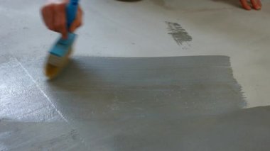 İnşaatçı boyacı astar beton zemin. İşçi boyanın altındaki zemini hazırlıyor.