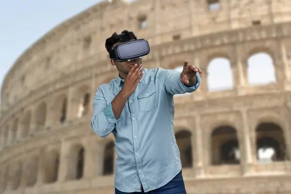 Young man wearing virtual reality goggles. Ancient historical architecture in the background. People, technology and innovation concept.