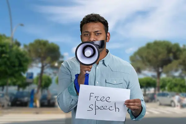 タップされた口を持つ若者は 屋外で立っているメガフォンに話しかけようとします フリースピーチコンセプト — ストック写真