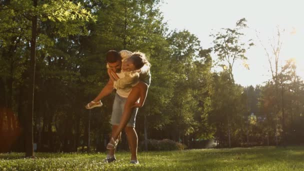 Sevgililer Gün Batımında Parkta Yürürler Kız Oğlanların Sırtında Eğleniyorlar Daireler — Stok video