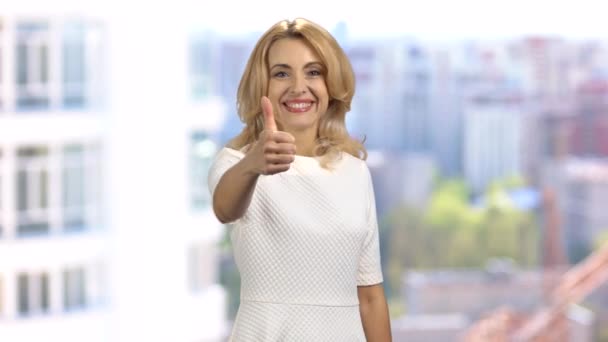 Szczęśliwa Blondynka Uśmiechnięta Dojrzała Kobieta Stojąca Domu Podnosząca Kciuk Zamazany — Wideo stockowe