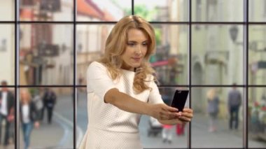 İçeride selfie çeken sarışın bir kadının portresi. Avrupa şehir manzaralı pencere.