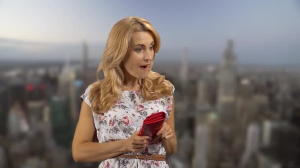 兴奋的女人从她的红皮夹里拿钱 背景中的城市景观 — 图库视频影像