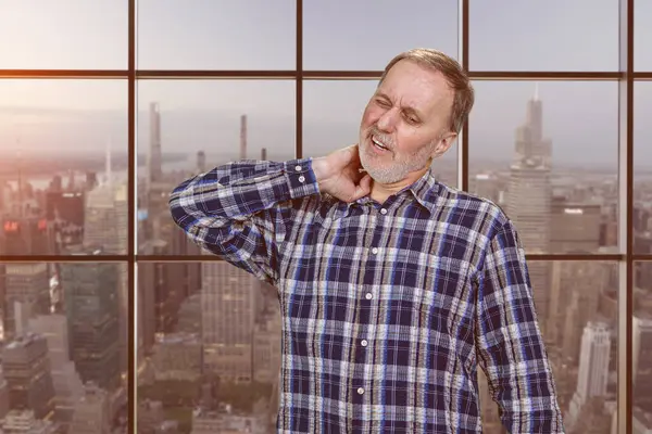 Handsome Mature Caucasian Man Having Neckache Checkered Windows Background Cityscape Royalty Free Stock Images