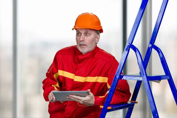 코카서스 노동자의 초상화는 태블릿 장치를 사용하고 있습니다 특별한 유니폼에 남자는 스톡 사진