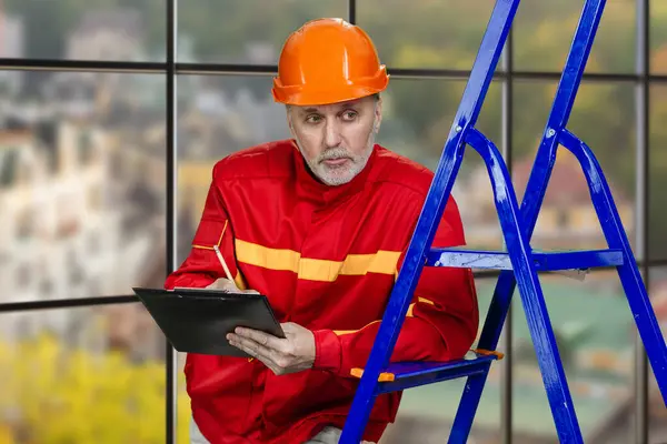 Portrait Mature Caucasian Worker Tablet Blue Contruction Ladder Checkered Window ロイヤリティフリーのストック画像