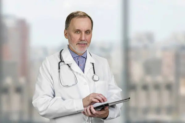 Portrait Mature Senior Male Doctor Holding Digital Tablet Standing Indoors ストックフォト