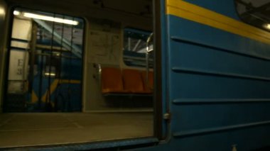 Modern bir metro treni istasyonda duruyor. Tren vagonları raylar boyunca dizildi, teknisyenler tekerlekleri ve şasiyi kontrol ediyor..