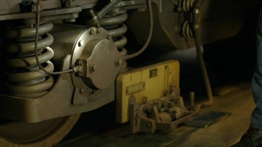 Metrodaki tekerlekleri ve fren sistemini kontrol ediyorum. Bir teknisyen gerekli tamirat için metro tekerleklerini ve frenlerini kontrol eder..