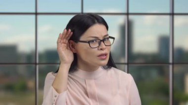 Asyalı etnik kökenli genç bir şirket çalışanı iş kadını seni dinliyor. Arka plandaki kapalı pencere.