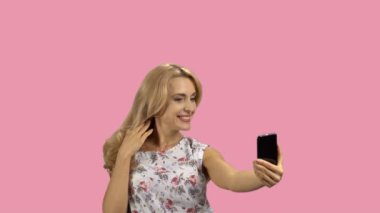 Mutlu sarışın kadın akıllı telefon kamerasıyla selfie çekiyor. Kırmızı ışıkta izole edilmiş..