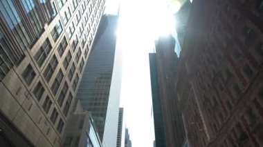 Parlak güneş ışığı New York 'un merkezindeki yüksek binaları gözetliyor. Modern cam gökdelenler, dekoratif tarihi mimarinin yanında duruyor, şehrin stil karışımını sergiliyorlar..