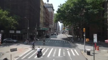 New York City, New York, ABD - 08.01.2024: Bisikletçiler, araçlar ve yayaların bulunduğu bir New York kavşağı. Yeşillik ve mimarinin karışımı şehirleri yansıtıyor.