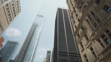 Manhattan şehir merkezindeki gökdelenlerin manzarası etkileyici mimarilerini açık bir gökyüzüne karşı sergiliyor. Resim, tarihi taşın yanındaki modern cam ve çelik binaları vurguluyor.