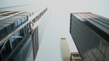 New York 'ta yükselen gökdelenlerin dramatik manzarası. Bu resim, gökyüzüne karşı parlak, modern mimari çizgileri ve yansıtıcı cam yüzeyleri sergiliyor..