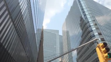 New York, Manhattan 'ın Finansal Bölgesi' ndeki lüks, modern gökdelenlerin çarpıcı manzarası. Cam ve çelik cepheler parlak gökyüzünü ve etrafındaki binaları yansıtıyor.