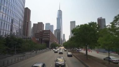 New York City, New York, ABD - 08.01.2024: Manhattan şehir merkezinde modern binalarla çevrili bir şehir manzarası. Araçlar, yeşilliklerle çevrili işlek cadde boyunca ilerliyor.